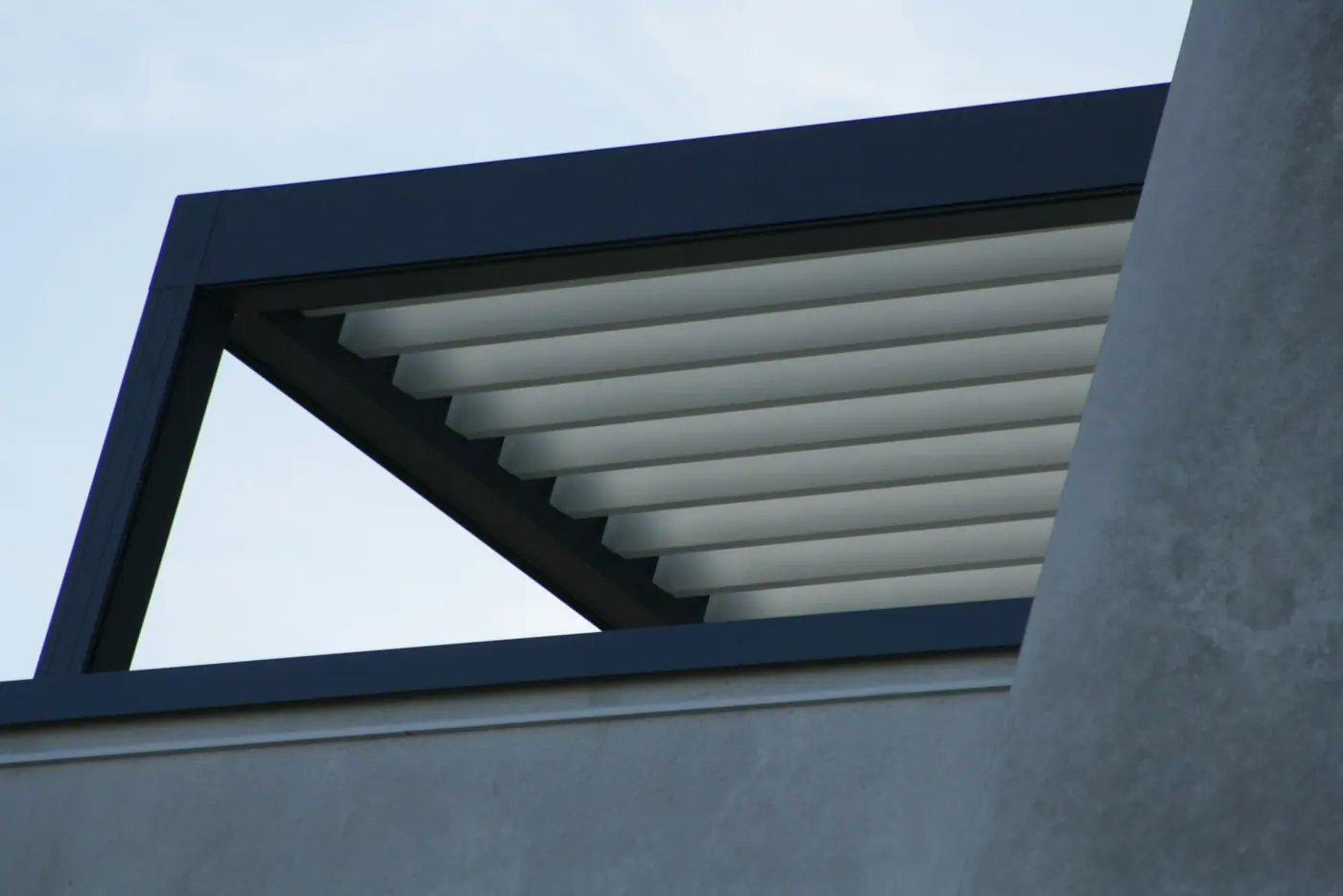 Cubierta de lamas blancas en una estructura de aluminio oscuro sobre una terraza